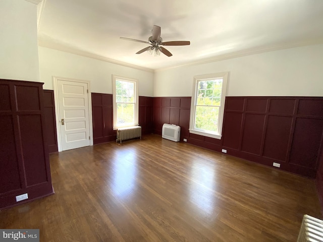 unfurnished room with radiator, crown molding, dark wood-type flooring, and a healthy amount of sunlight