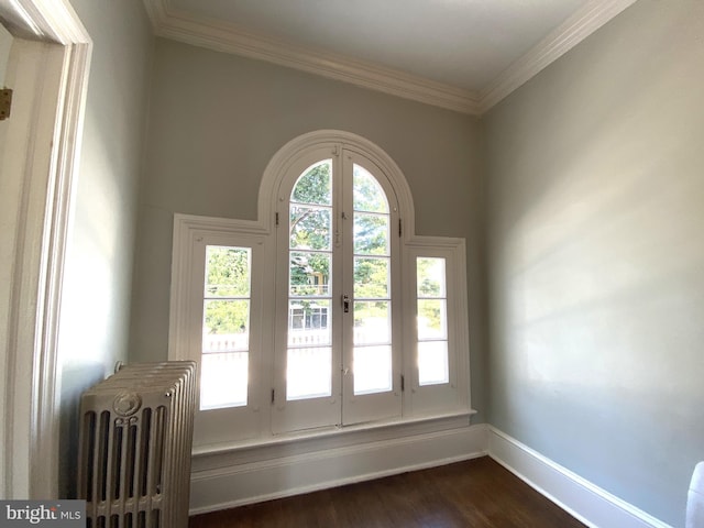 entryway with dark wood-type flooring, crown molding, and radiator