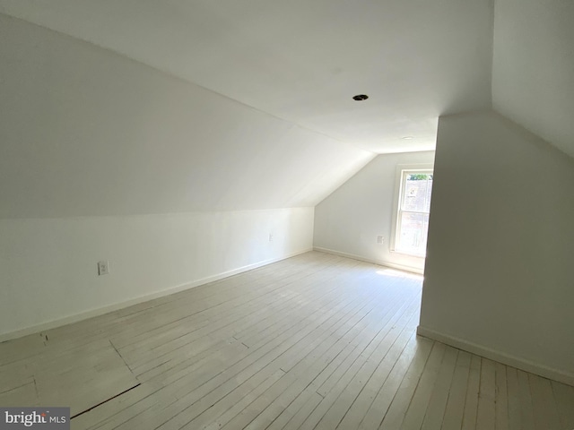 additional living space featuring lofted ceiling and light hardwood / wood-style flooring