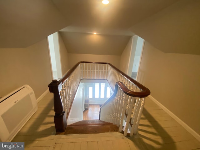 stairs with hardwood / wood-style flooring, a wall mounted air conditioner, and vaulted ceiling