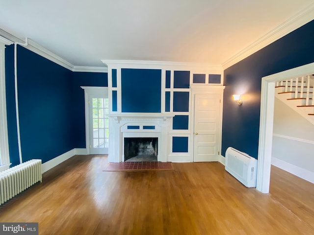 unfurnished living room with hardwood / wood-style flooring, ornamental molding, and radiator heating unit