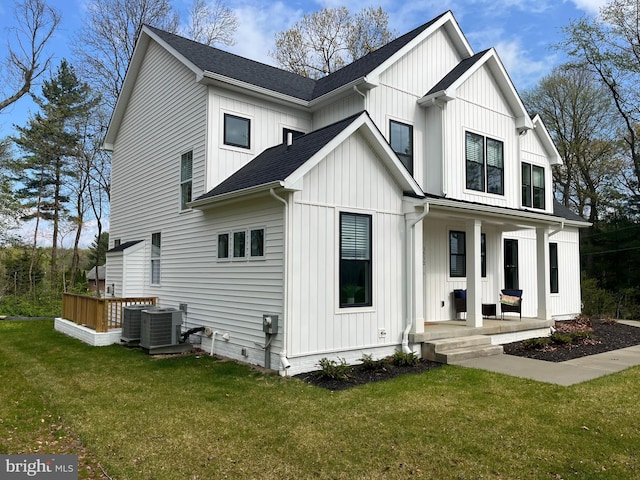 back of house featuring a porch, cooling unit, and a lawn