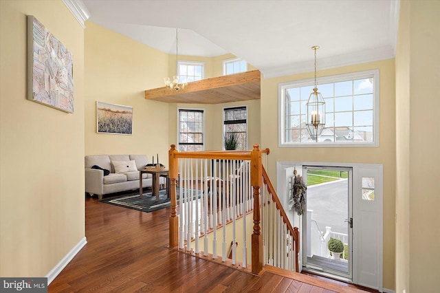 interior space featuring a towering ceiling, ornamental molding, dark hardwood / wood-style flooring, and a chandelier