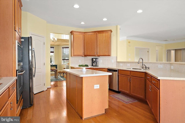 kitchen featuring sink, light hardwood / wood-style flooring, appliances with stainless steel finishes, a center island, and tasteful backsplash