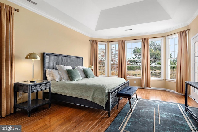 bedroom with a raised ceiling, crown molding, and hardwood / wood-style floors