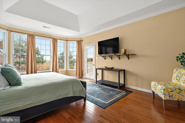 bedroom with ornamental molding, wood-type flooring, and a tray ceiling