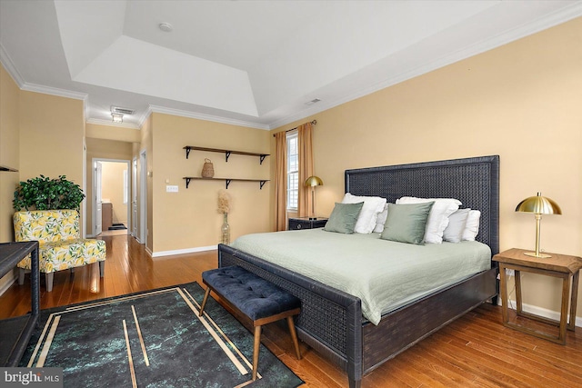 bedroom with crown molding, wood-type flooring, and a raised ceiling