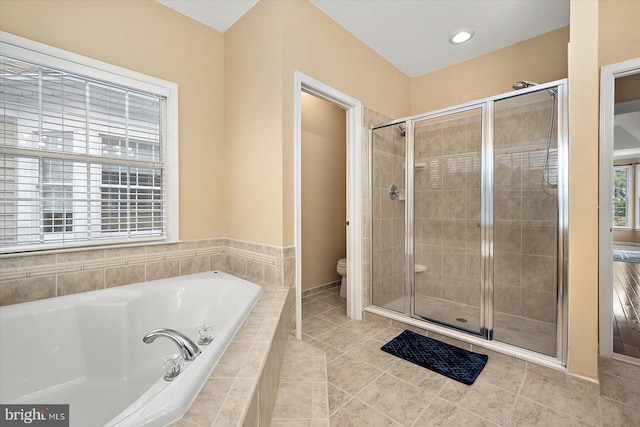 bathroom featuring toilet, tile patterned flooring, and shower with separate bathtub