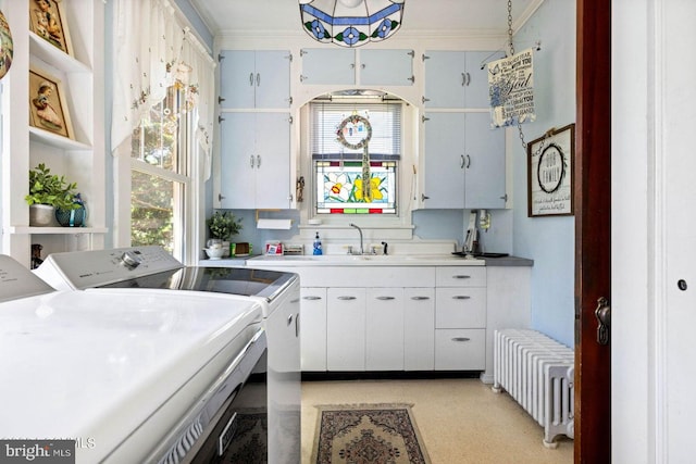 kitchen featuring radiator, decorative light fixtures, white cabinetry, washing machine and clothes dryer, and plenty of natural light