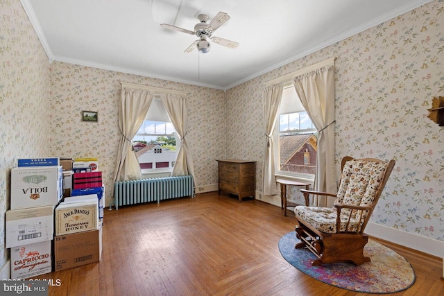 living area with ceiling fan, a wealth of natural light, radiator heating unit, and ornamental molding