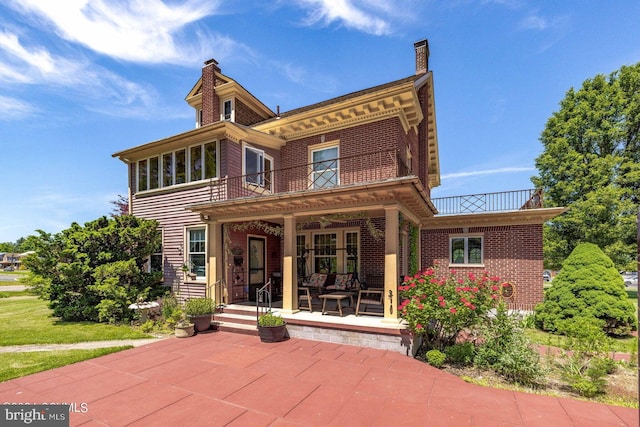 back of property with a balcony and a patio