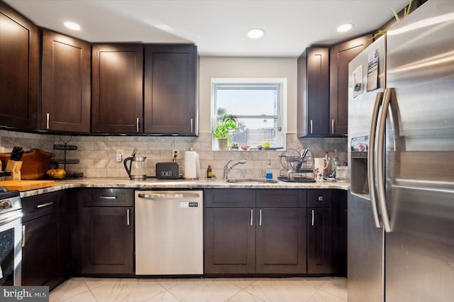 kitchen with appliances with stainless steel finishes, backsplash, dark brown cabinets, light stone counters, and sink