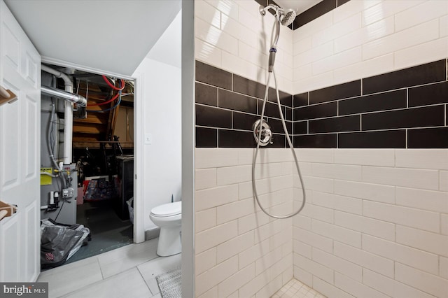 bathroom featuring toilet, a tile shower, and tile patterned flooring