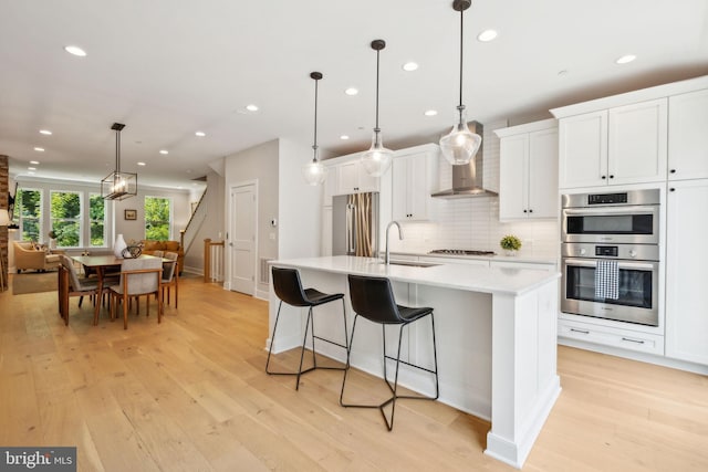 kitchen featuring a center island with sink, pendant lighting, sink, and appliances with stainless steel finishes