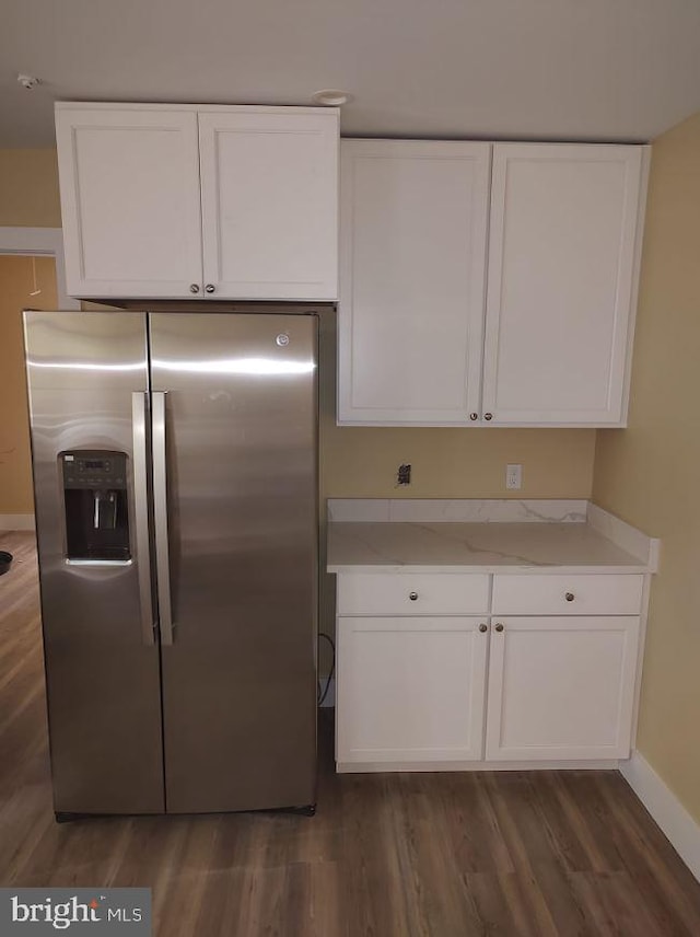 kitchen featuring light stone counters, white cabinets, dark hardwood / wood-style floors, and stainless steel refrigerator with ice dispenser