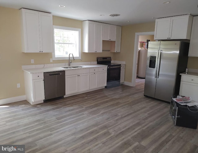 kitchen featuring stainless steel appliances, white cabinetry, light hardwood / wood-style floors, and sink