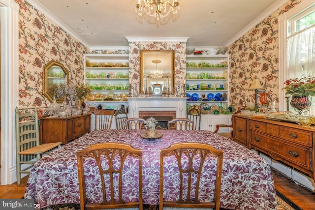 dining space featuring ornamental molding, hardwood / wood-style flooring, a brick fireplace, and a notable chandelier