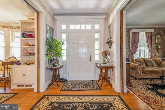 entryway with light hardwood / wood-style floors, a healthy amount of sunlight, and ornamental molding