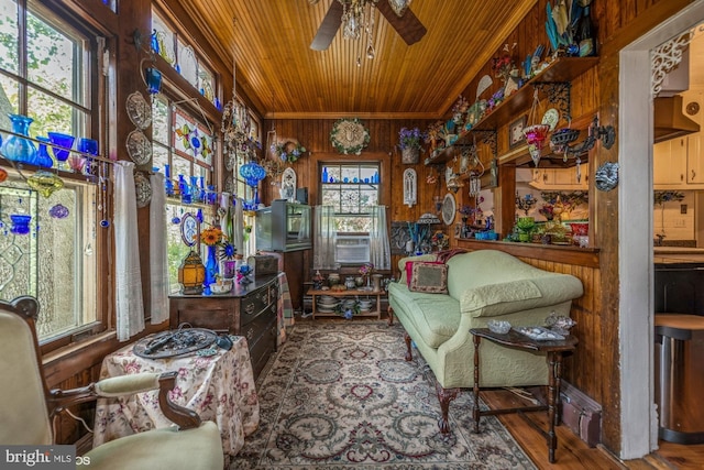 sitting room with wooden ceiling, crown molding, wooden walls, hardwood / wood-style flooring, and ceiling fan