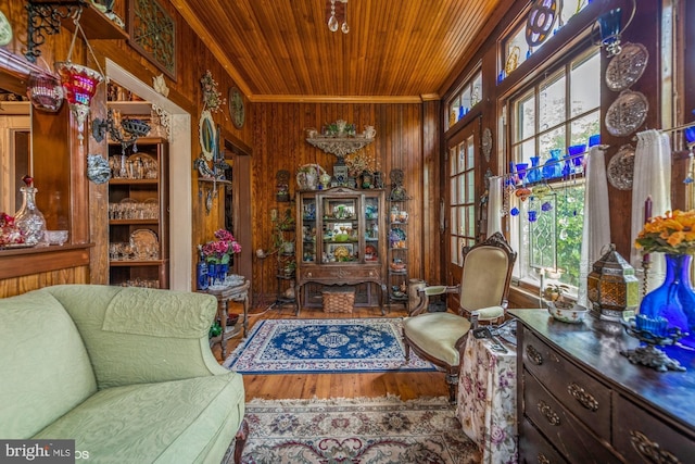 sitting room featuring wood-type flooring, crown molding, wooden ceiling, and wood walls