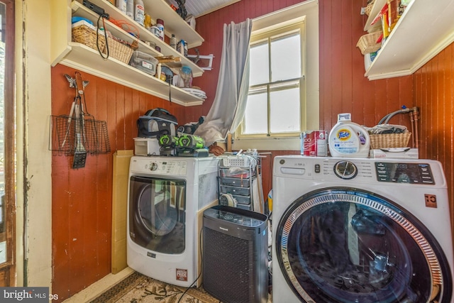 clothes washing area with separate washer and dryer and wooden walls