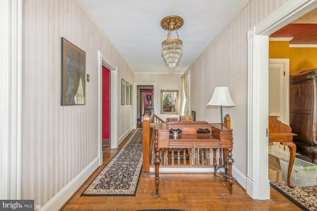 corridor with hardwood / wood-style flooring, ornamental molding, and a chandelier