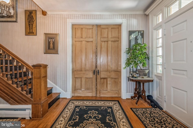 entrance foyer with baseboard heating, crown molding, and light hardwood / wood-style flooring