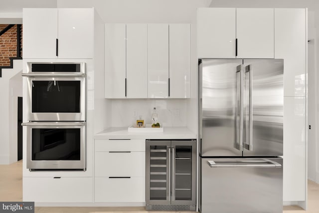 kitchen with white cabinets, backsplash, stainless steel appliances, and wine cooler