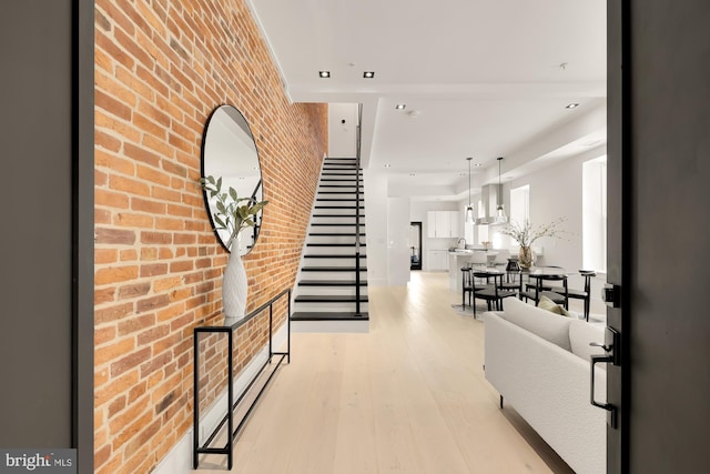 hall featuring sink, light hardwood / wood-style flooring, and brick wall