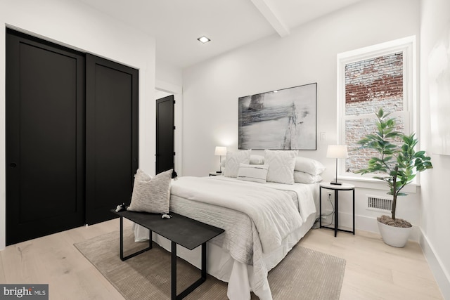 bedroom featuring beam ceiling and light hardwood / wood-style flooring