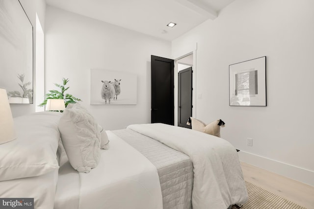 bedroom featuring beam ceiling and light wood-type flooring