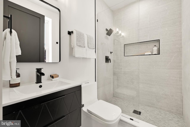 bathroom with toilet, vanity, and tiled shower