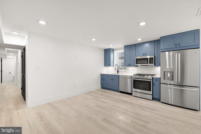 kitchen featuring sink, blue cabinets, stainless steel appliances, and light hardwood / wood-style flooring