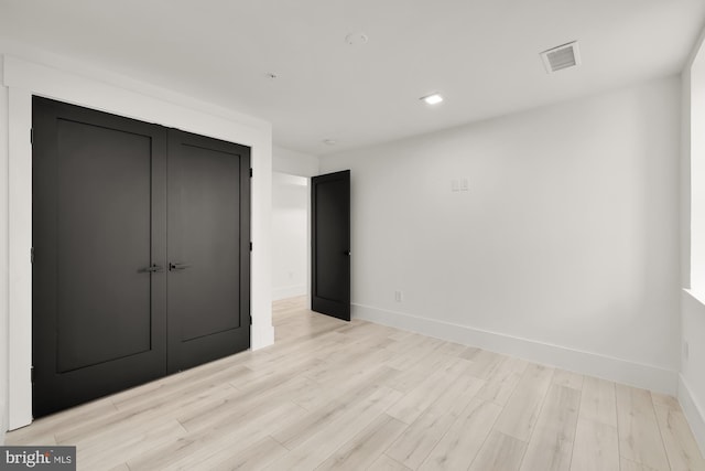 unfurnished bedroom featuring light wood-type flooring and a closet