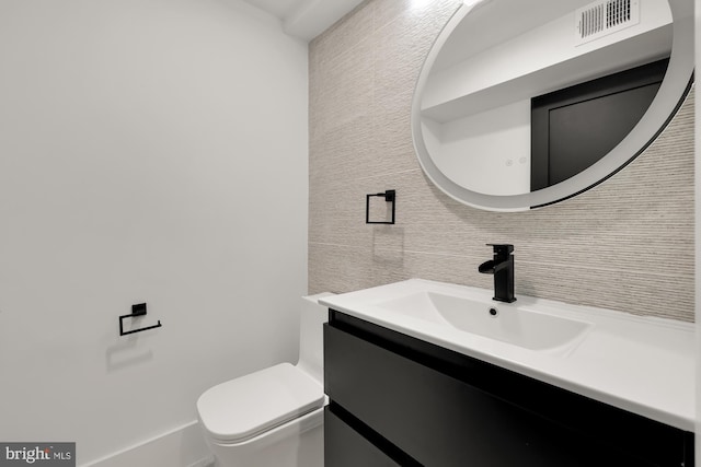 bathroom with vanity, toilet, and backsplash