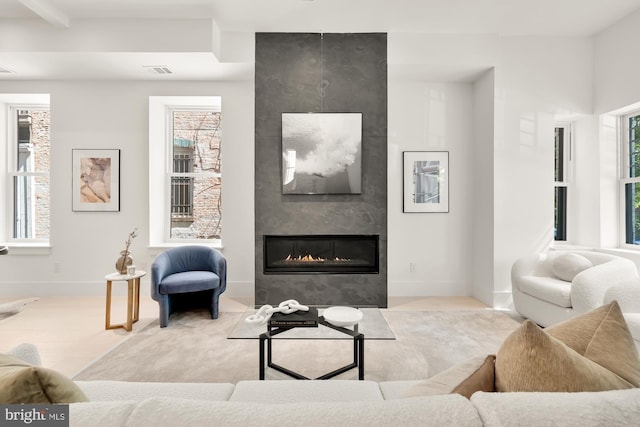 living room with beam ceiling, a wealth of natural light, and a fireplace