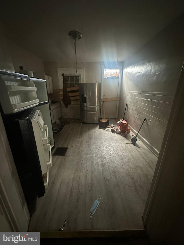 basement featuring stainless steel fridge and hardwood / wood-style floors