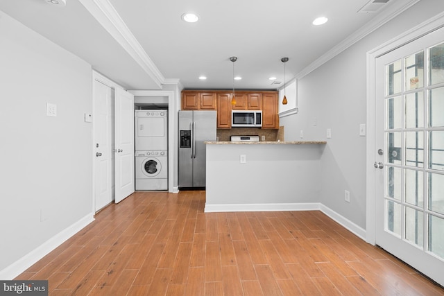 kitchen featuring kitchen peninsula, light stone countertops, stainless steel appliances, stacked washer and clothes dryer, and hanging light fixtures