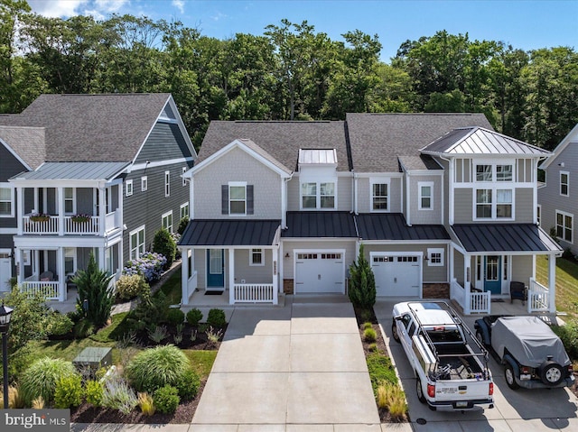 multi unit property with driveway, a standing seam roof, an attached garage, and covered porch