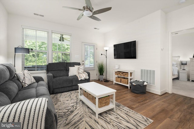 living room featuring dark wood-type flooring, visible vents, and baseboards