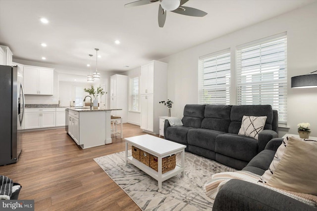 living room with light wood-style flooring, ceiling fan, and recessed lighting