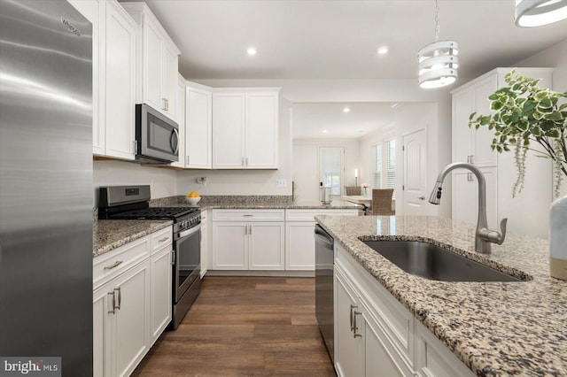 kitchen with pendant lighting, stainless steel appliances, a sink, and white cabinets