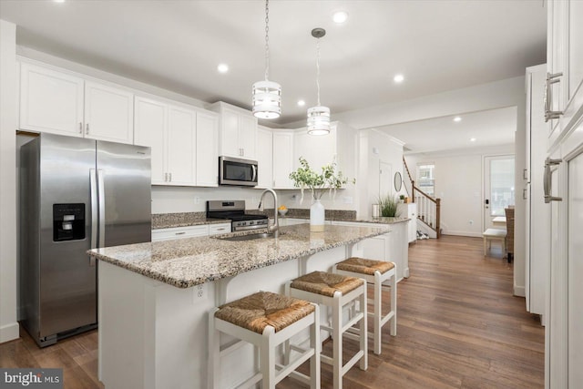 kitchen featuring stainless steel appliances, hanging light fixtures, a sink, and white cabinetry