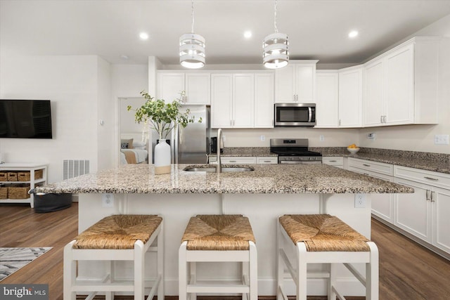 kitchen featuring pendant lighting, a breakfast bar, a kitchen island with sink, sink, and appliances with stainless steel finishes