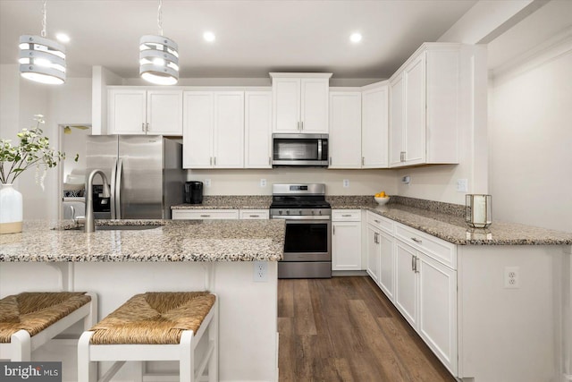 kitchen with light stone countertops, white cabinetry, stainless steel appliances, and decorative light fixtures