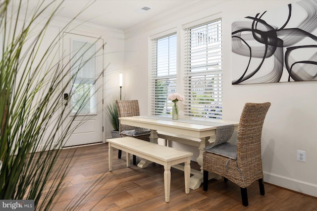 dining room featuring baseboards, visible vents, dark wood finished floors, and crown molding