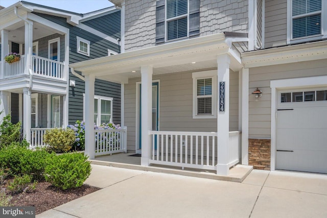 doorway to property with a garage, stone siding, and a porch