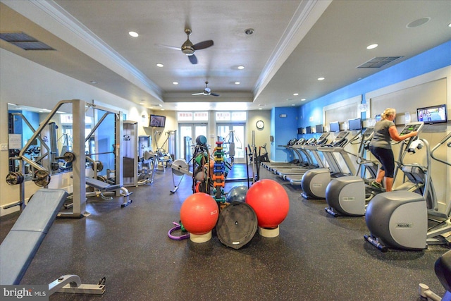 gym with a raised ceiling, ceiling fan, and crown molding