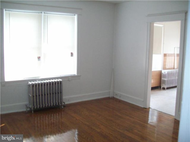 unfurnished room with dark hardwood / wood-style floors and radiator