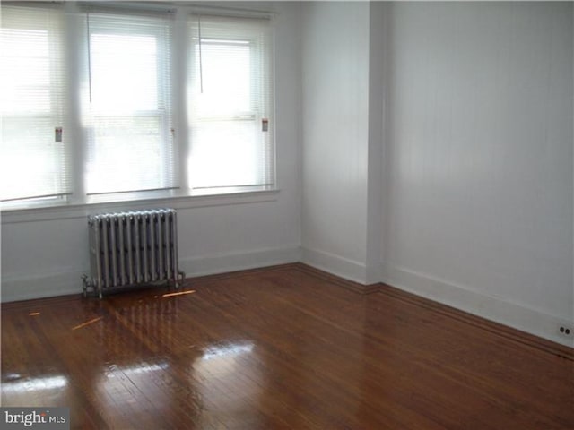 spare room featuring radiator and dark wood-type flooring